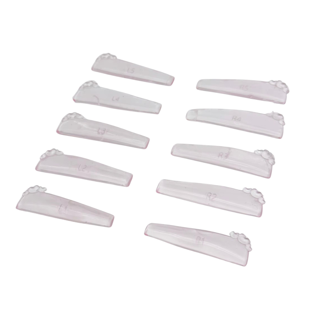 Ten clear plastic nail tips with short curved shapes and decorative claw-like ends, arranged on a plain white background.