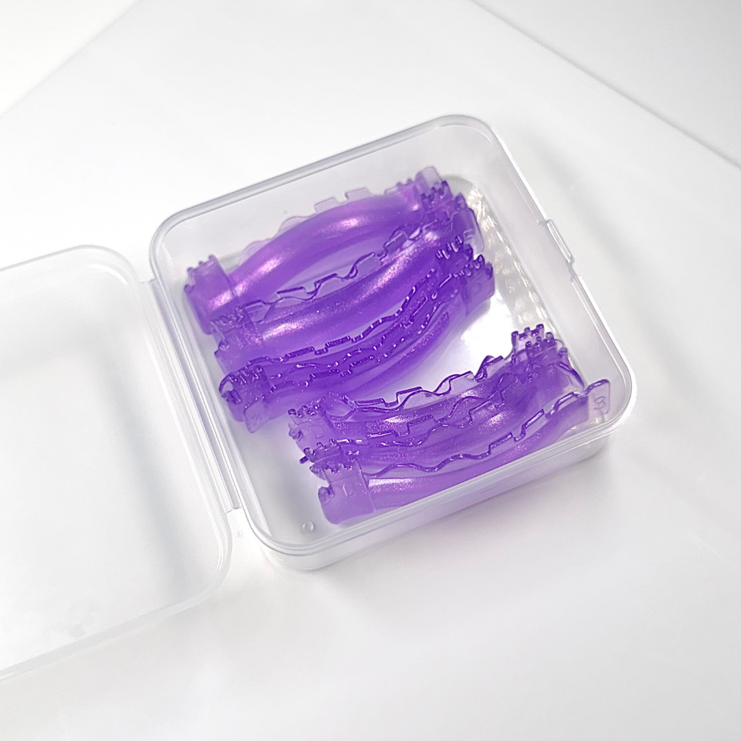 Two purple textured silicone sleeves inside a clear plastic storage case, shown on a white background.
