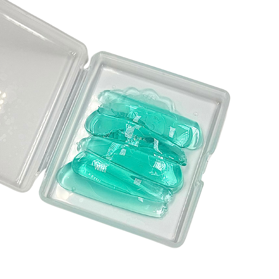 Five translucent mint green gel mouthguards arranged inside an open clear plastic case on a white background.
