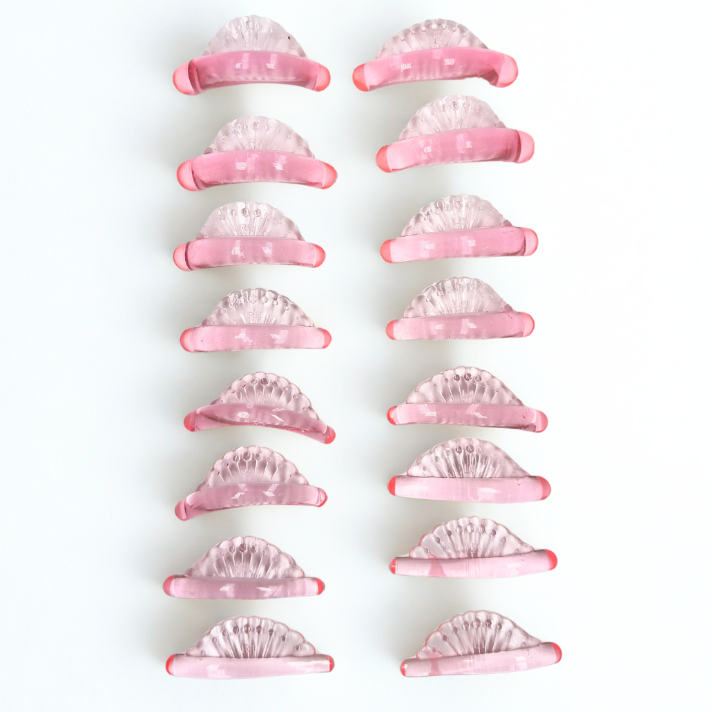 Twelve pink and clear crescent-shaped hair claw clips arranged in two vertical columns on a plain white background.