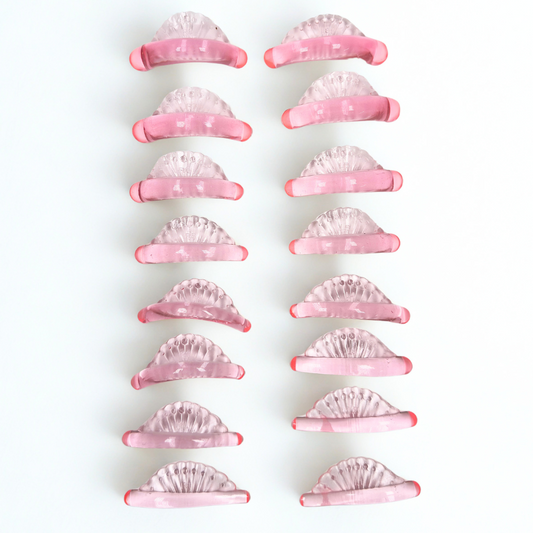 Twelve pink and clear crescent-shaped hair claw clips arranged in two vertical columns on a plain white background.